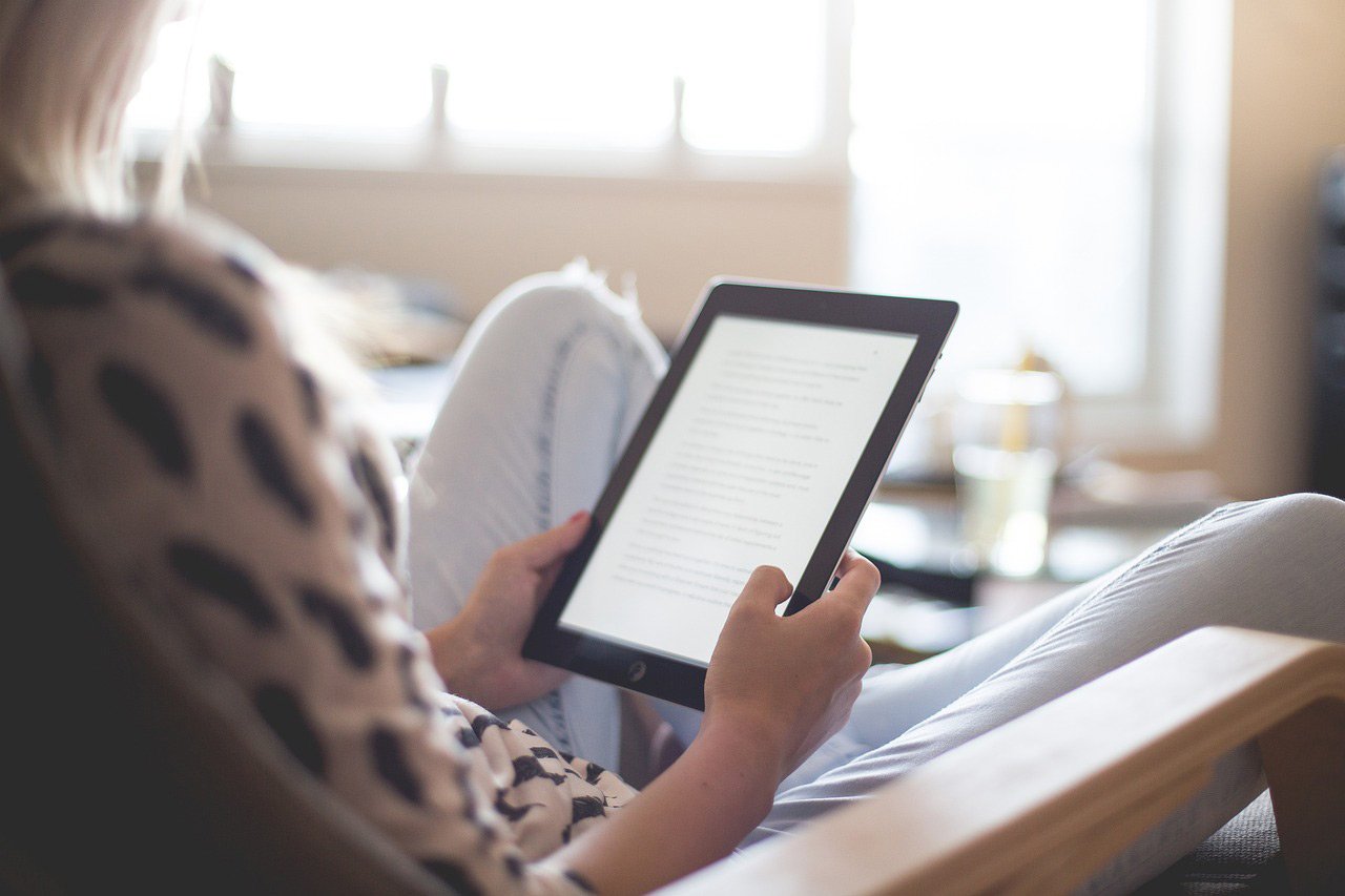 woman sitting at home reading her ipad